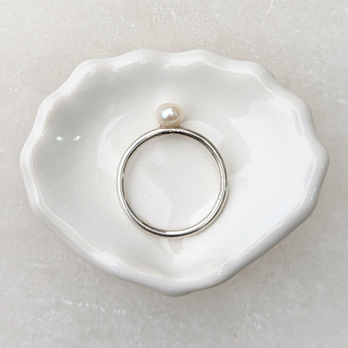 silver round pearl ring laid flat on trinket dish