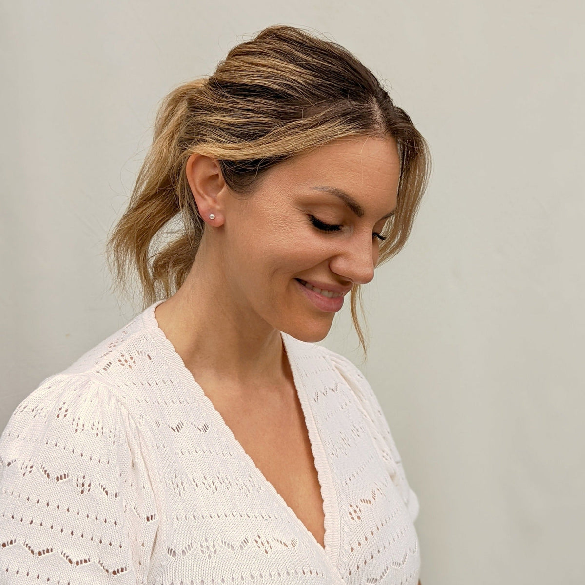 Model wearing white top and tiny pearl earring