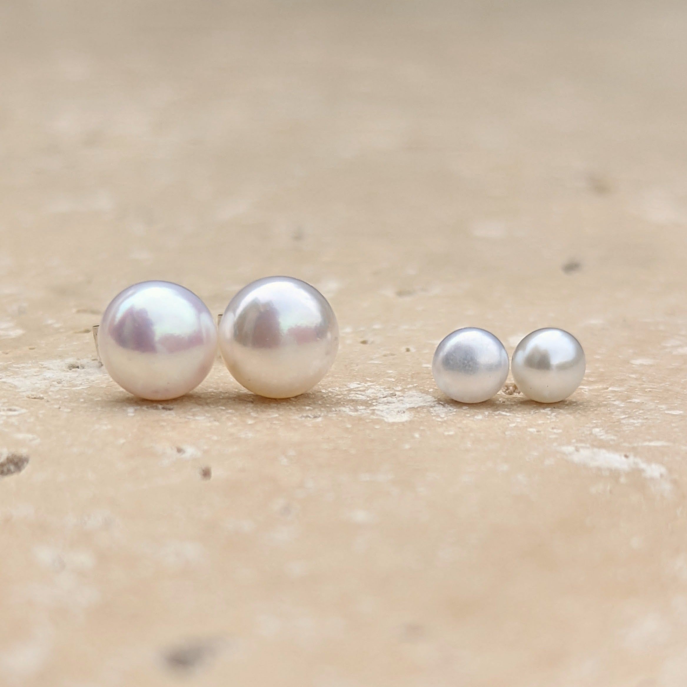 Size comparison between two pairs of round button pearl stud earrings