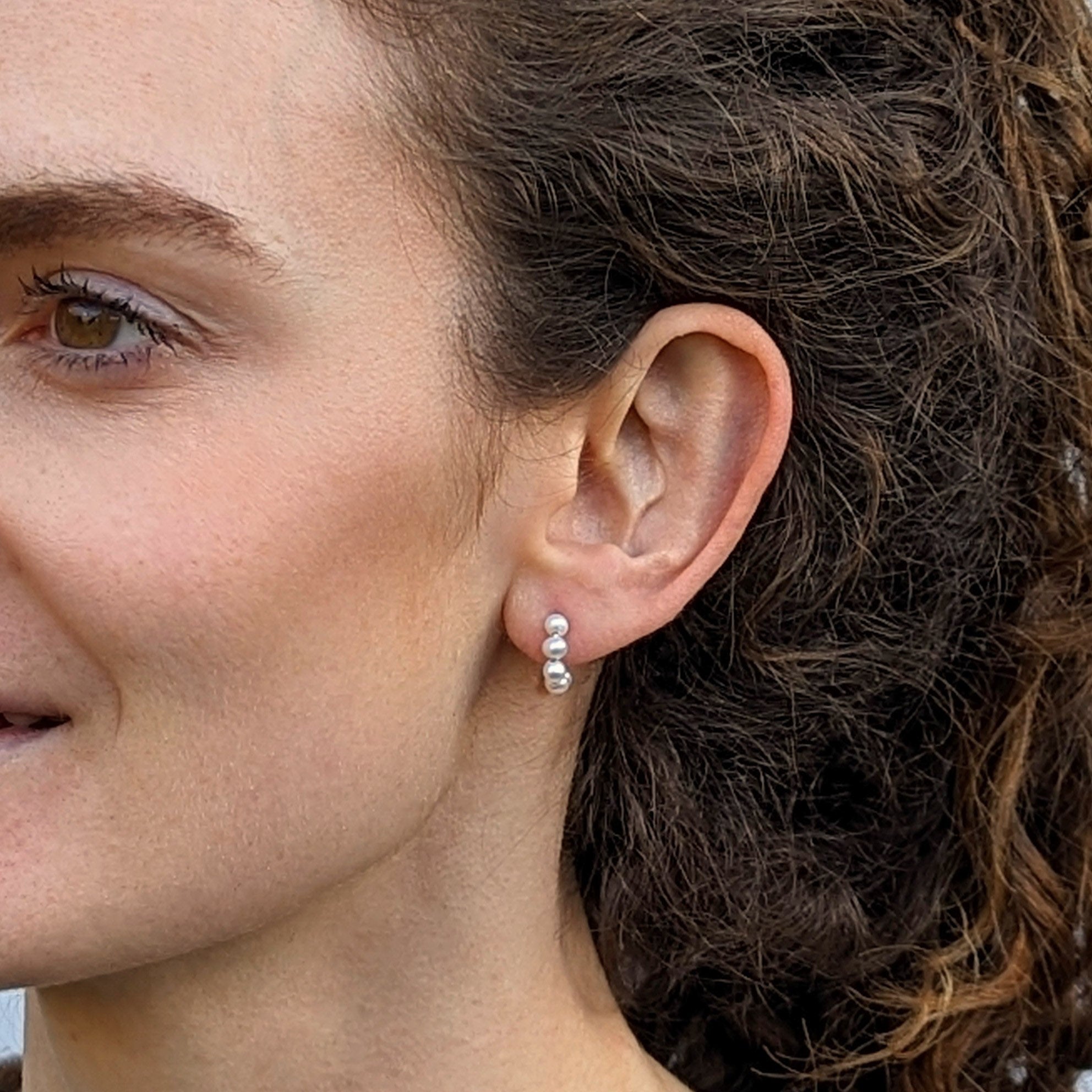 Model with curly hair wearing pearl stud hoop earrings